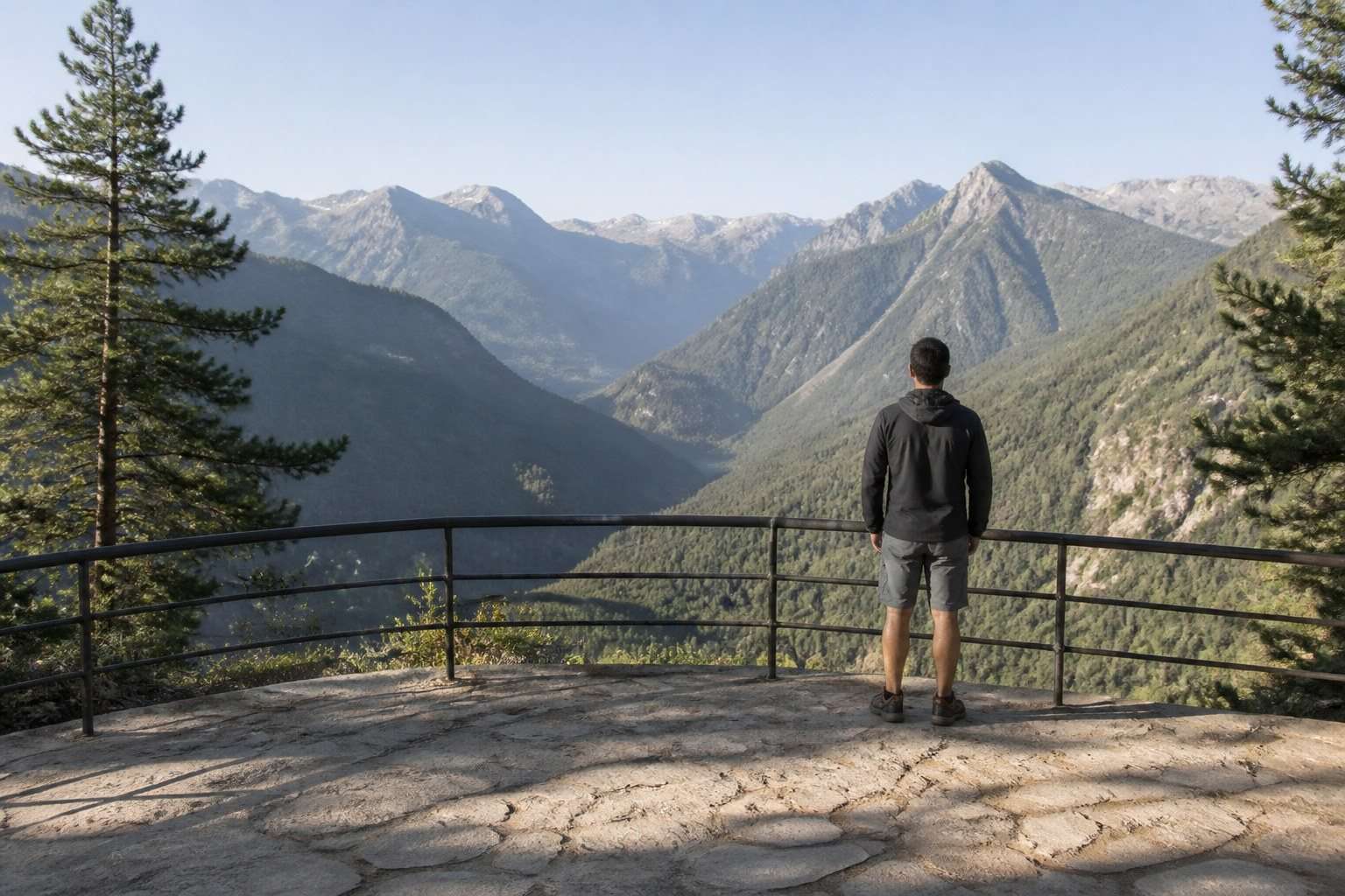 Excursionista contemplando un valle desde un mirador protegido